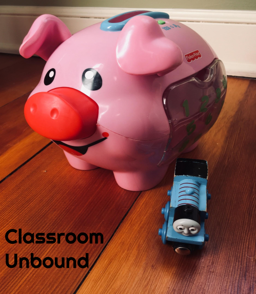 Experiential Learning Depot blog post photo with a Thomas the Train Toy in front of a piggy bank.