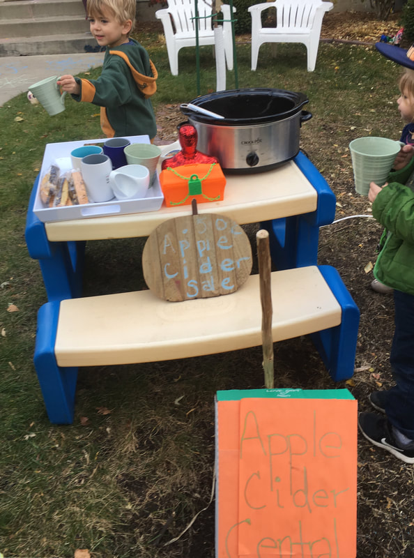 Photo of a four year old serving apple cider at his apple cider stand on a cold fall day.