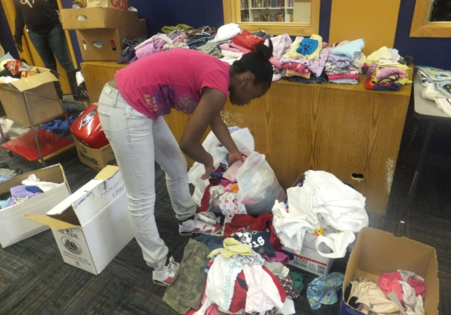 A student organizing a bag of donated clothing for a school rummage sale. 