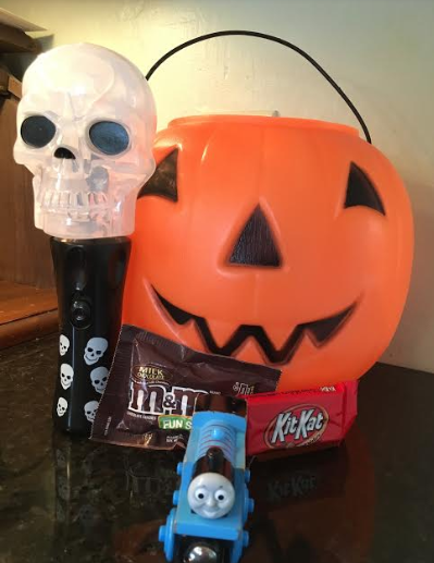 An Experiential Learning Depot created photo with a Thomas the Train toy sitting in front of a pumpkin and a skull flashlight.